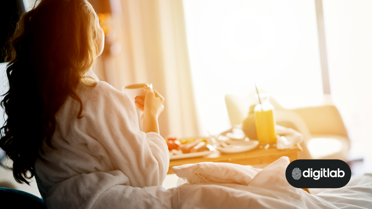 marketing for hotels - woman in bed holding a cup of coffee looking out a hotel window.