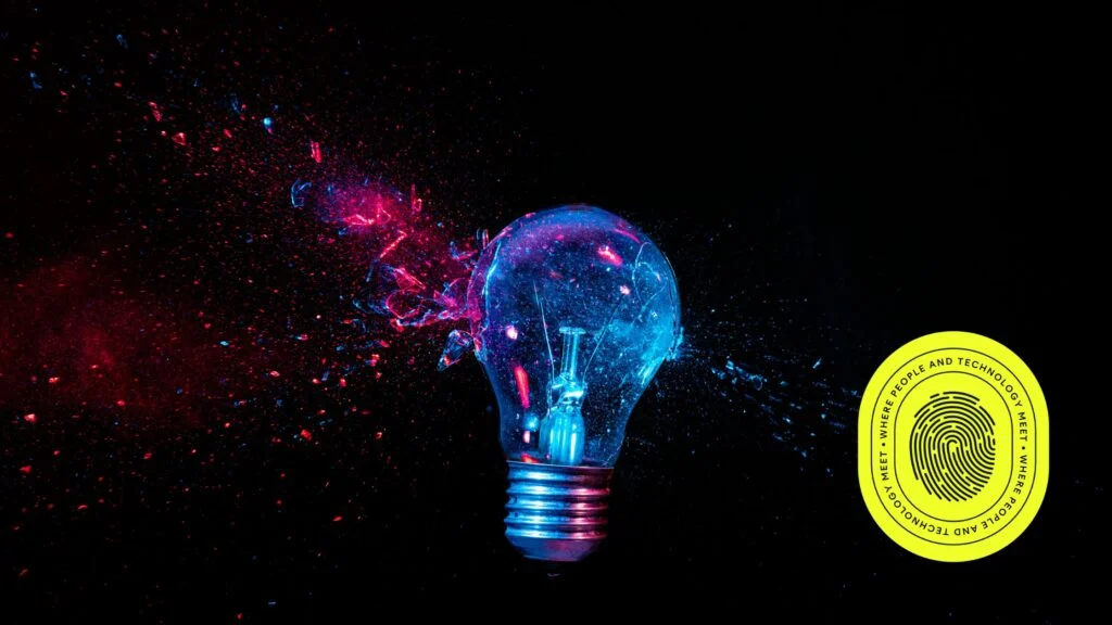 A vibrant image of a shattered lightbulb emitting blue and pink sparks against a black background, symbolizing innovation and transformation. A yellow circular badge on the bottom right corner displays the phrase "Where people and technology meet" with a fingerprint graphic, aligning with the theme of "Insight 2025