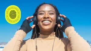 Smiling young woman with braids listening to music on headphones under a clear blue sky, symbolizing clarity and optimism—reflecting the SEO impact of changing domain names for a refreshed digital identity.