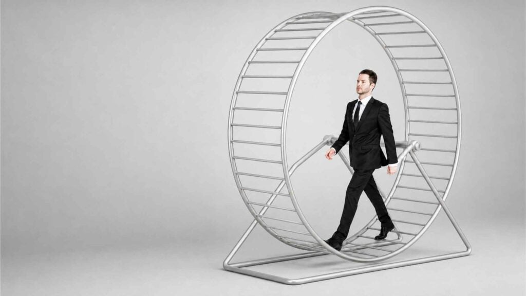 Businessman in a suit walking inside a hamster wheel, symbolizing marketing reporting that shows activity without real business progress