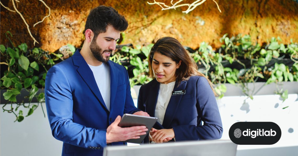 Hotel Search Engine Marketing - man and woman standing at hotel reception desk looking at an ipad.